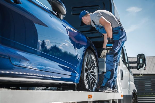 car-repossession-worker-securing-vehicle-on-his-towing-truck-e1697119541364.jpg