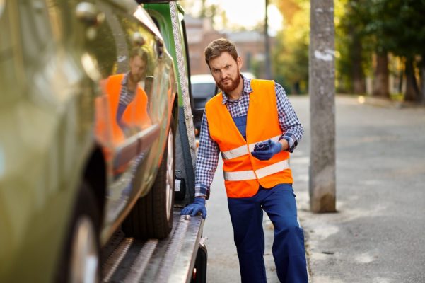 tow-truck-worker-checking-car-loading-accuracy-e1697119806868.jpg